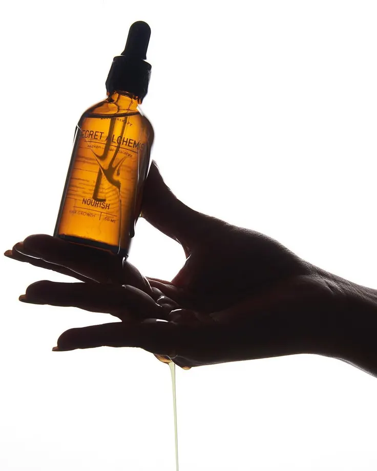 بطری اسپری روغن آرگان کنار مغز دانه آرگان