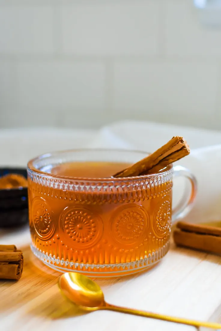 لیوان شیشه‌ای چای دارچین با چوب دارچین