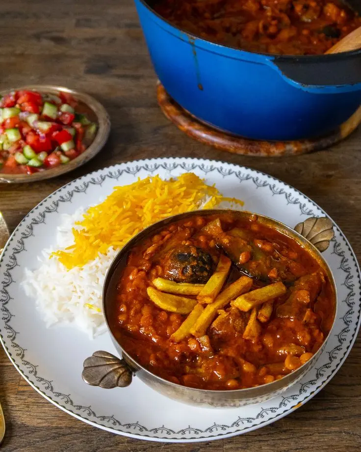 خورش بادمجان سرخ‌شده کنار قابلمه مسی و سالاد شیرازی