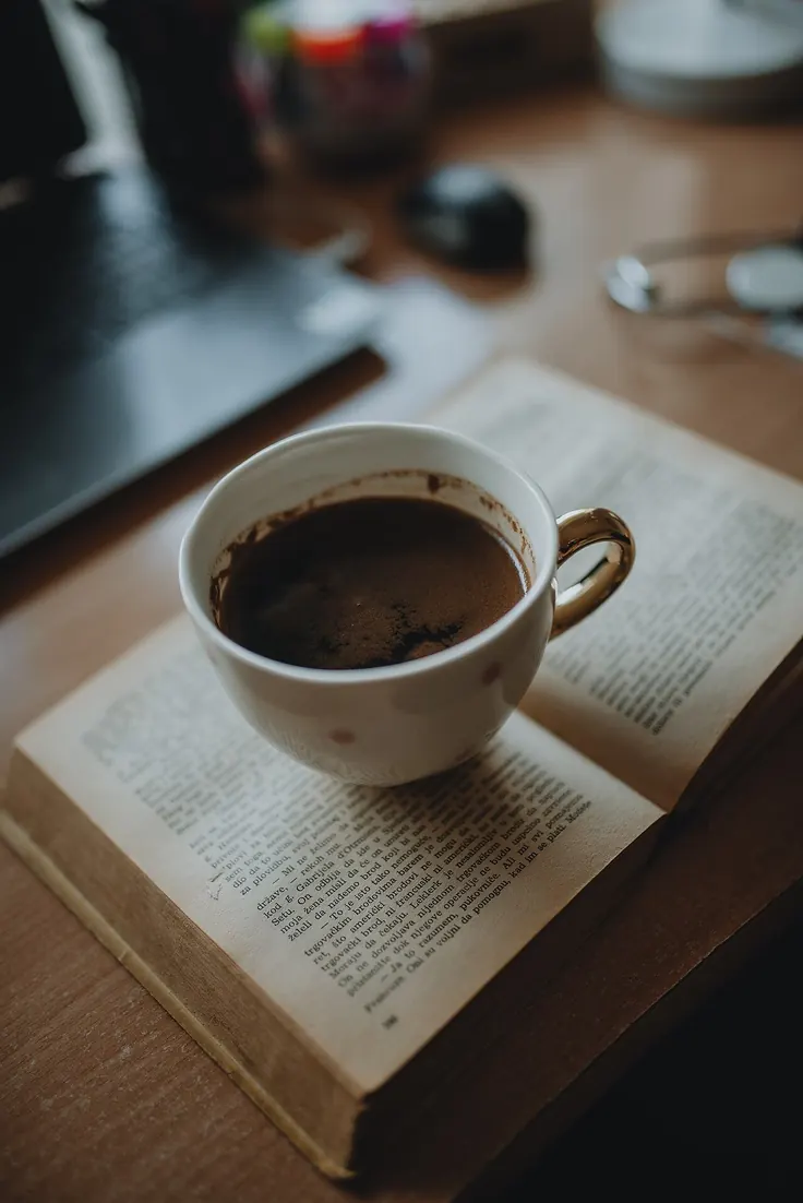 فنجان قهوه کنار کتاب باز و حس مطالعه آرام