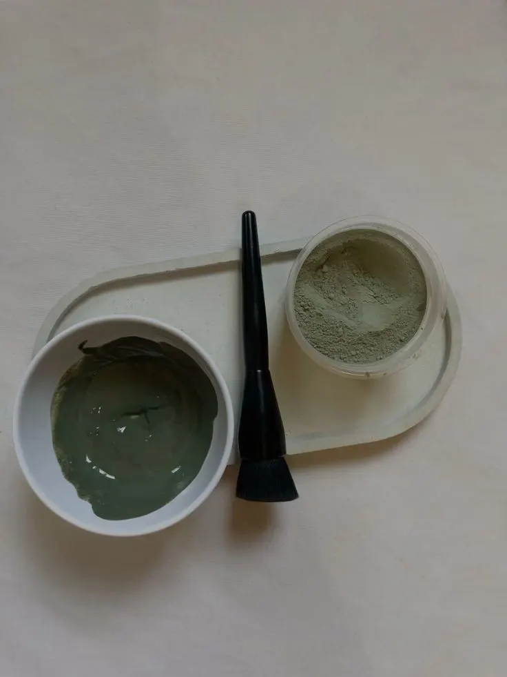 کاسه، قلم‌مو و پودر ماسک چای سبز روی دستمال