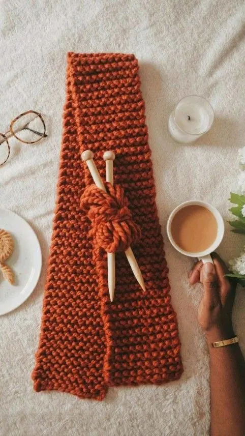 بافتنی شال گردن نارنجی با میل چوبی و فنجان چای روی روتختی