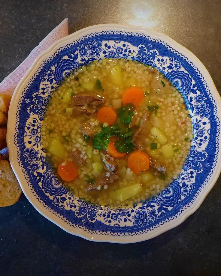 سوپ جو با نان تازه روی میز چوبی
